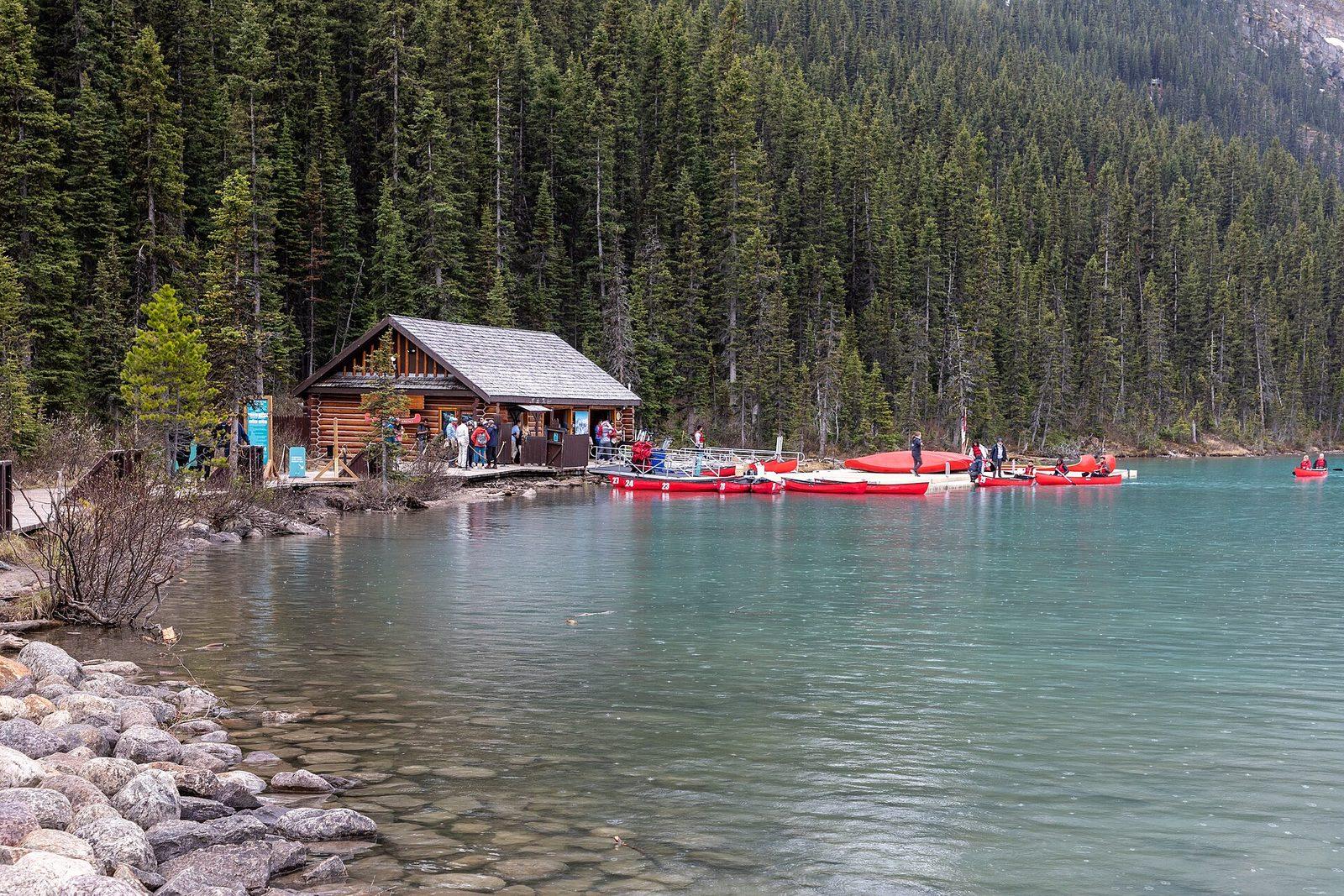 Lake Louise lakeshore boathouse with red canoes on turquoise glacial water
